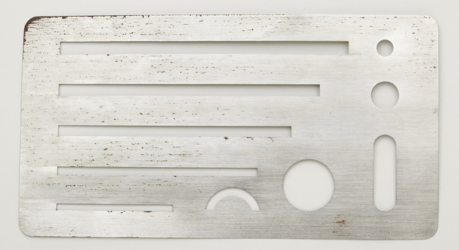 A stainless-steel erasing shield: only the mistake peeks through the slots.